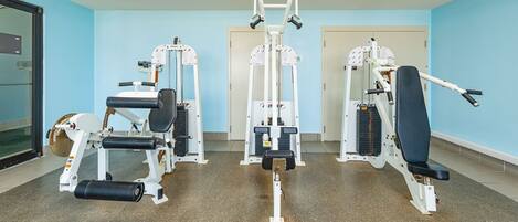 Un gimnasio con diferentes máquinas de ejercicio, una puerta y una ventana.