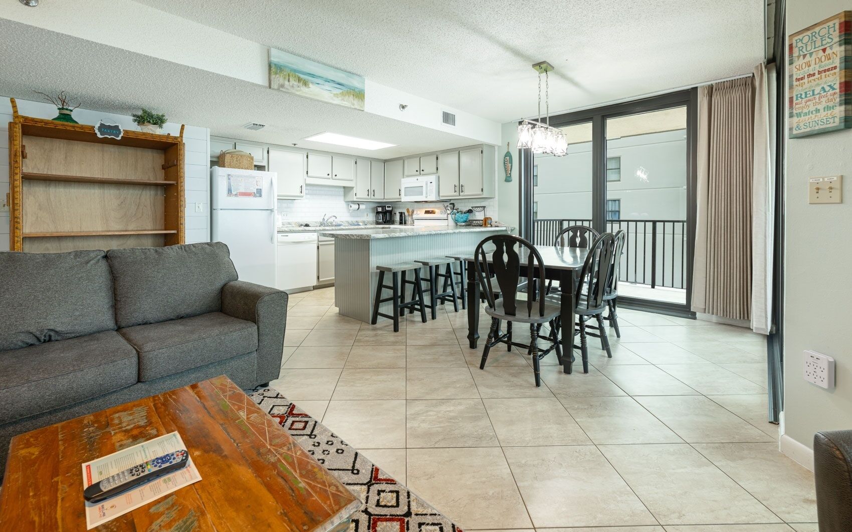 A modern kitchen with white cabinets, a central island, and a dining area with dark wooden chairs.