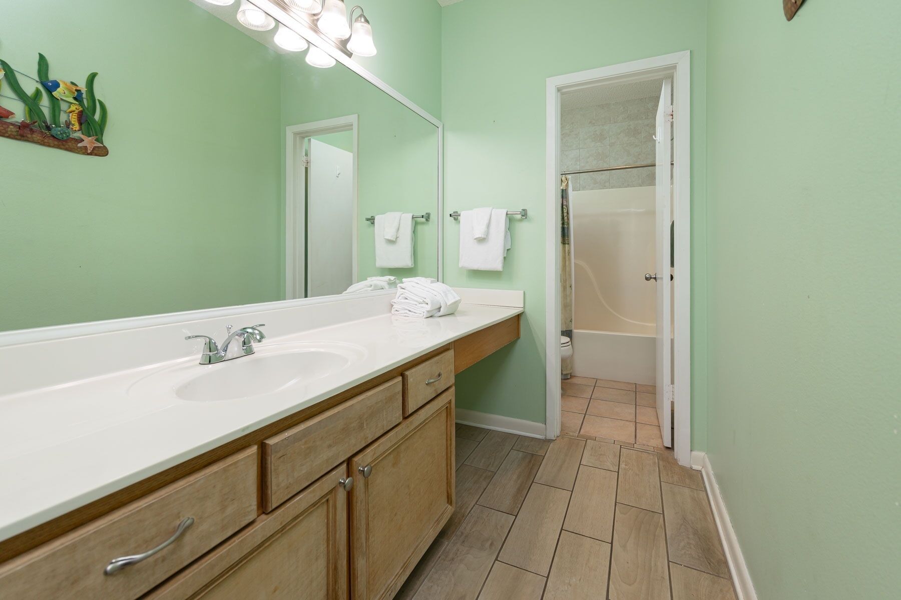 Une salle de bain avec un long lavabo, deux miroirs et une douche.