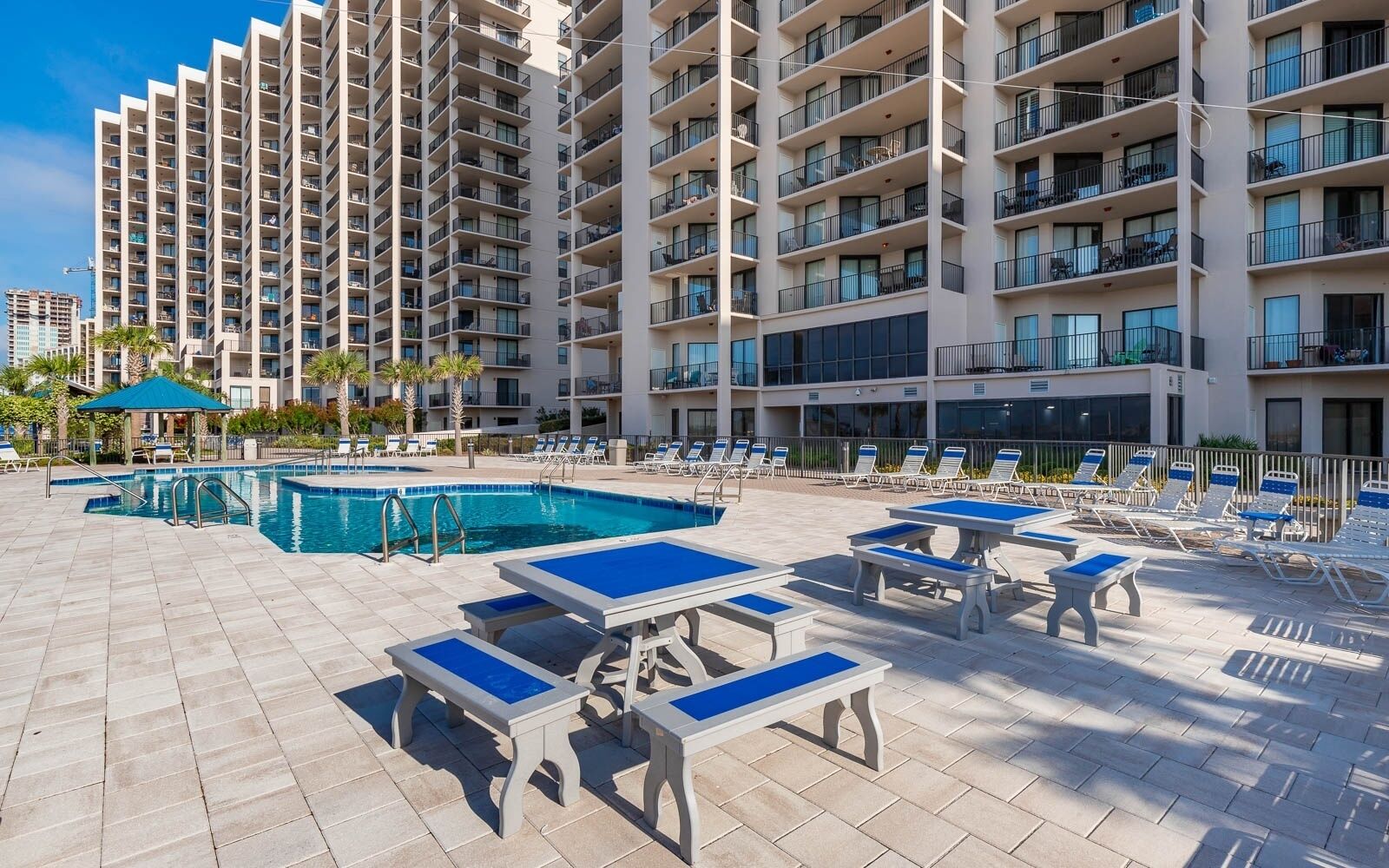 Un hotel con varios pisos, piscina y zonas de estar al aire libre con mesas y sillas.
