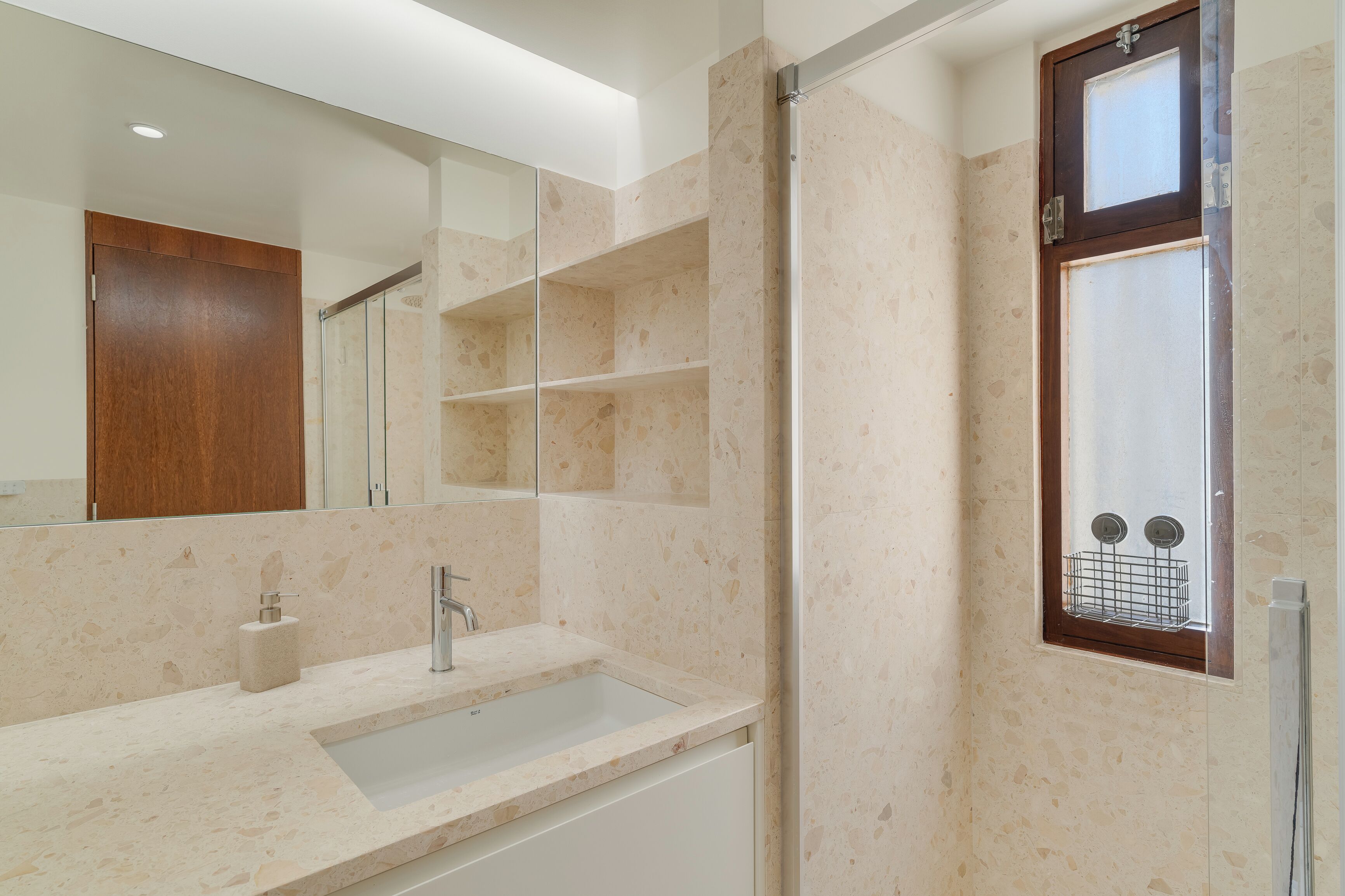 Une salle de bain moderne avec un grand miroir, un lavabo et un espace douche.