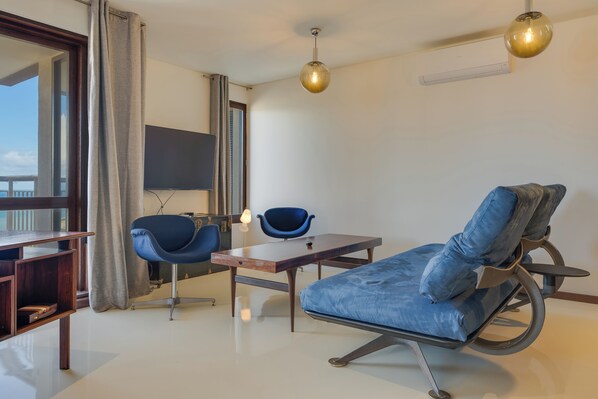Une pièce moderne comprenant un canapé, deux fauteuils, une petite table et un téléviseur.
