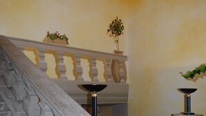 Een trap met een stenen balustrade en een gele muur.