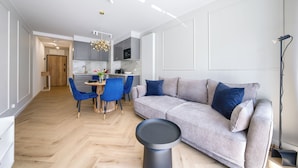 Uma sala de estar moderna com um sofá cinzento, cadeiras azuis e uma mesa de jantar.