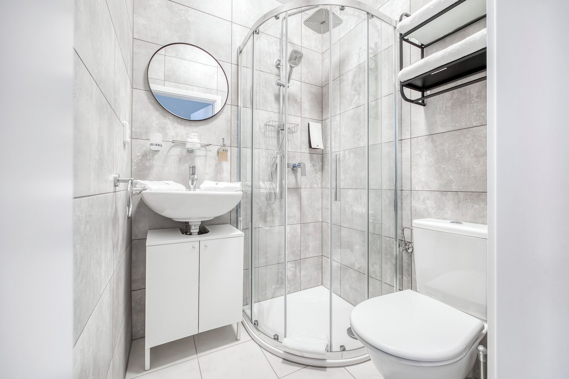 A modern bathroom with a glass-enclosed shower, a white sink, and a toilet.