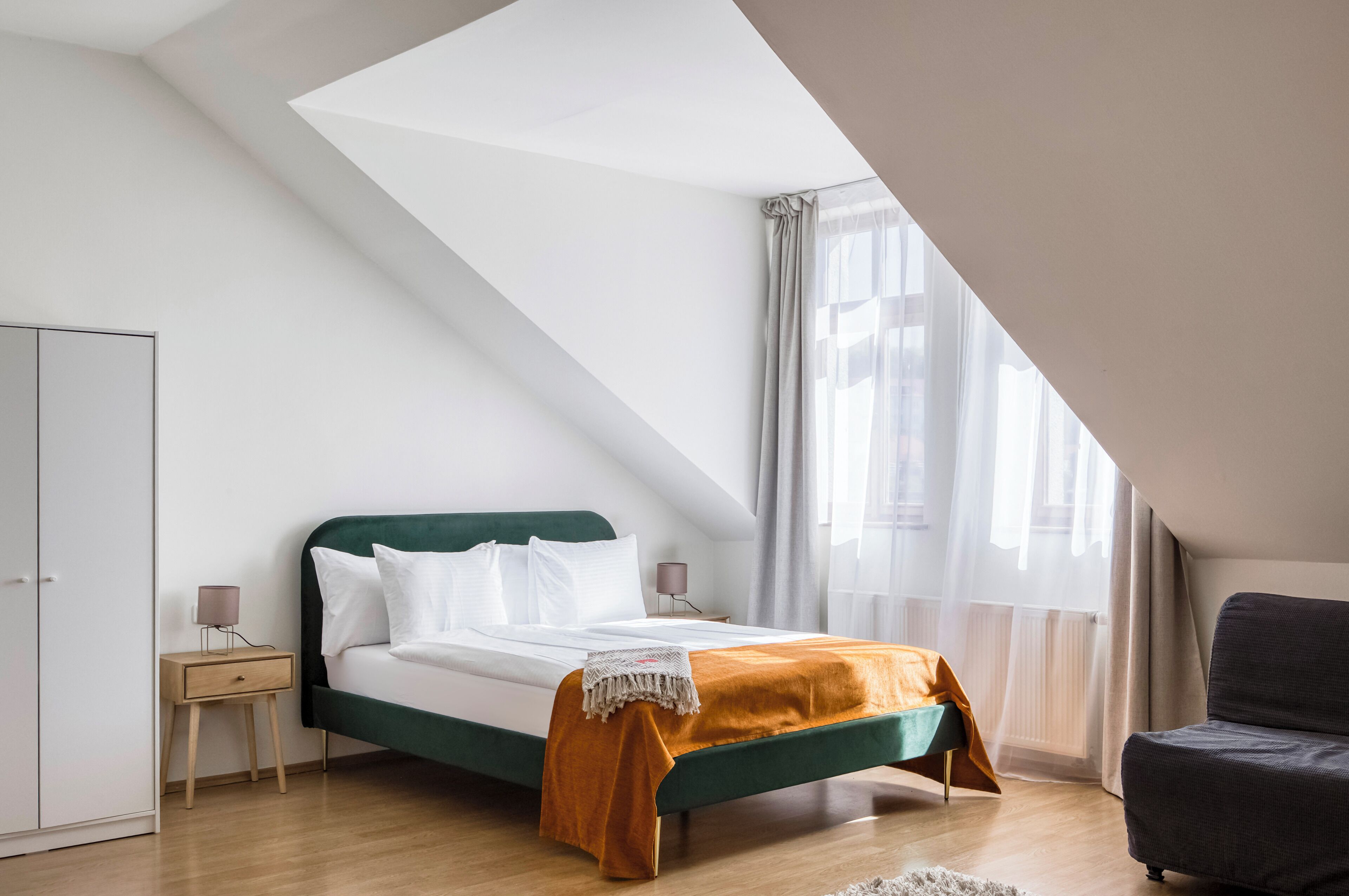 A bedroom with a bed, a nightstand, a chair, and a wardrobe.