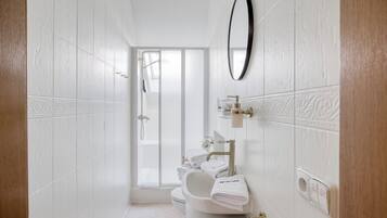 A modern bathroom with a shower, toilet, and sink, featuring white tiles and a large mirror.