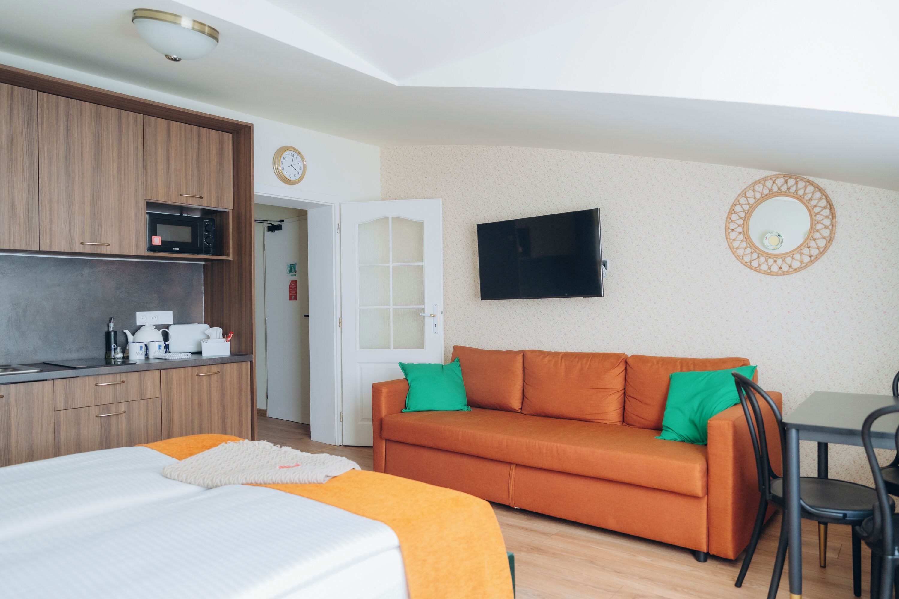 Ein kompaktes Hotelzimmer mit Küchenzeile, einer Sitzecke, einem Bett und einem Fernseher.
