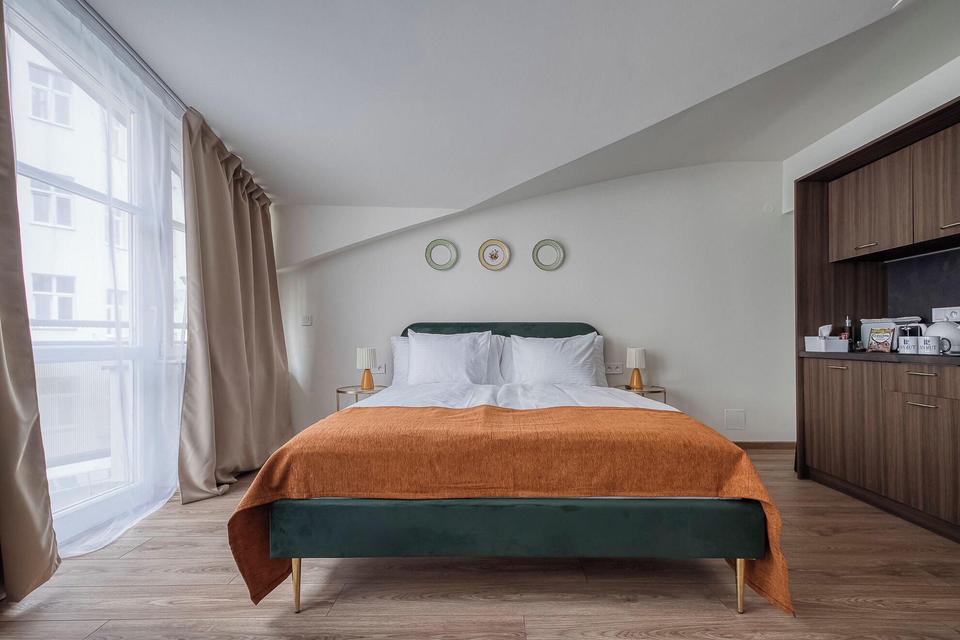 A bedroom with a bed, a window with curtains, a bedside table, and a wardrobe.