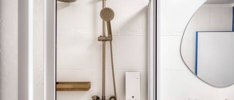 A bathroom with a glass-enclosed shower, a wall-mounted mirror, and a towel rack.