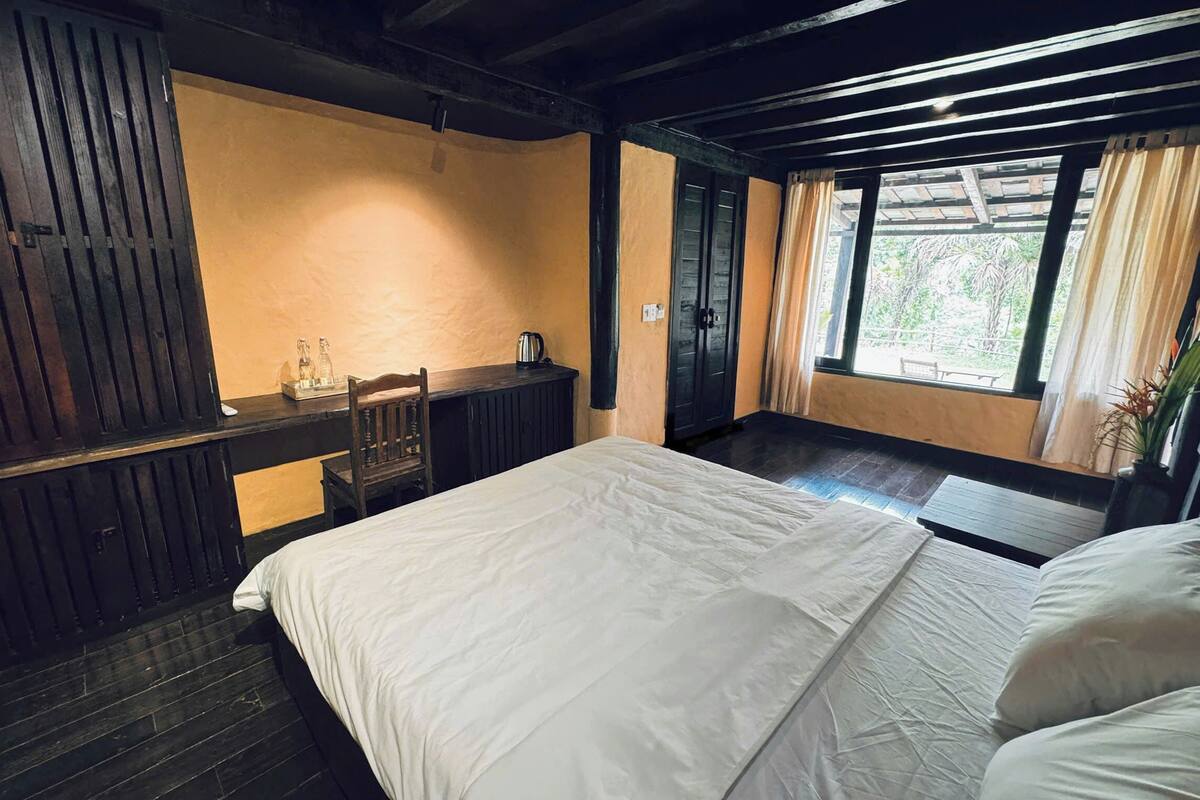 A room with a bed, a desk, and a window with curtains.