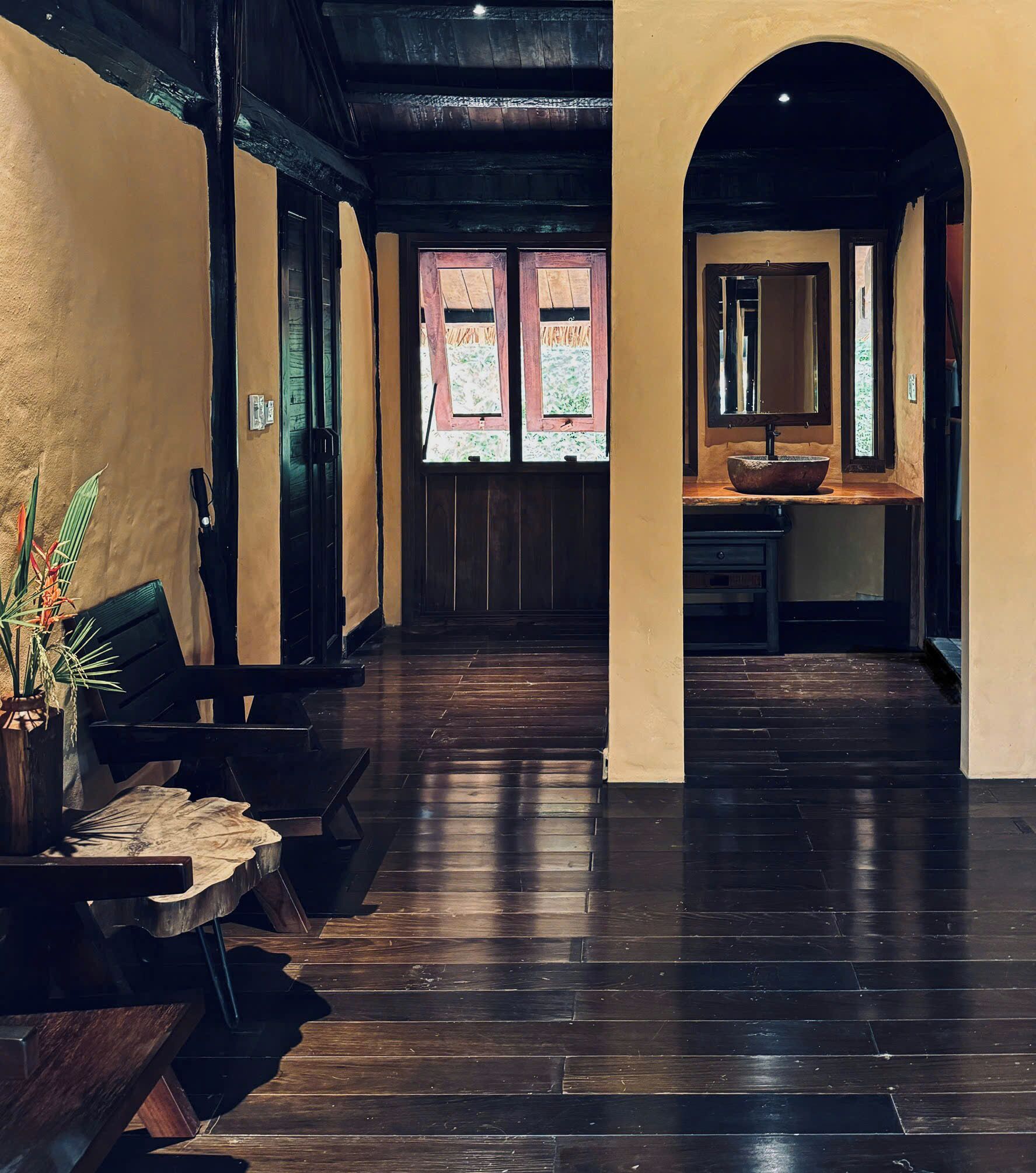 A hallway with wooden flooring, a bench, a potted plant, and a door with frosted glass panels.