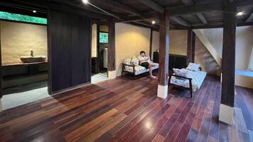 Une pièce spacieuse avec un plancher en bois, un canapé, un lit et une petite table.