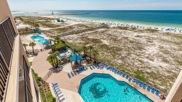 Un resort con varias piscinas, una zona de playa y vistas al océano.