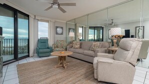 Ein geräumiges Wohnzimmer mit einer großen Couch, einem Sessel, einem runden Couchtisch und einem Balkon mit Blick.
