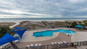 Ein Poolbereich mit Blick auf den Strand, Liegestühle und ein Pavillon.