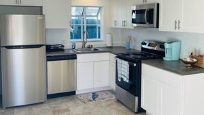 Una cocina moderna con electrodomésticos de acero inoxidable, armarios blancos y un ventanal que proporciona luz natural.