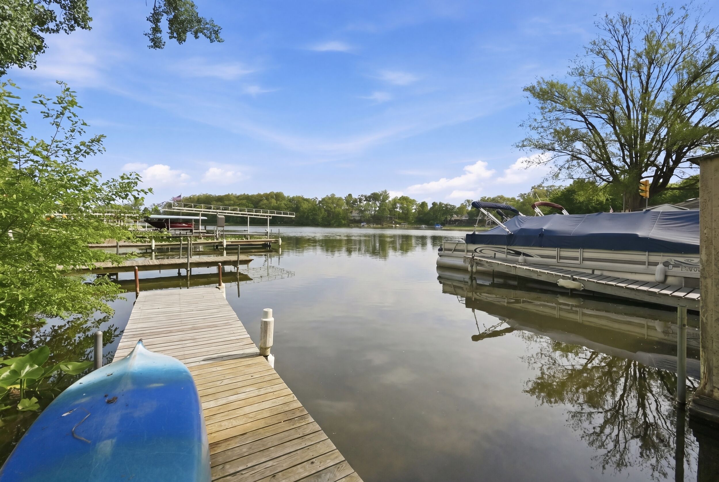 Un lac paisible avec un quai en bois, une rampe d’accès à l’eau abritée et un ciel dégagé.