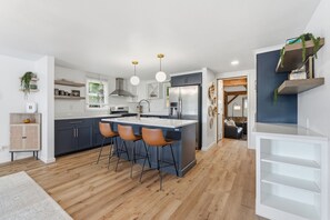 Une cuisine moderne dotée d’un îlot central, de tabourets de bar et d’un réfrigérateur encastré.