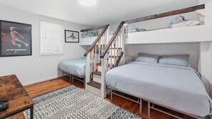 Une chambre avec des lits superposés, un escalier, un bureau et un tapis à motifs.