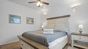 Ein Schlafzimmer mit Bett, Nachttischen, Deckenventilator und Wandlampen.