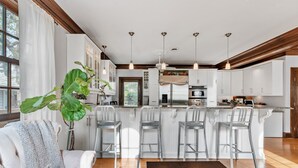 Een moderne keuken met witte kasten, roestvrijstalen apparatuur en een centraal eiland met barkrukken.