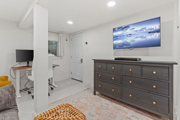 Una sala moderna con un televisor de pantalla plana, un aparador de madera oscura y una alfombra colorida.