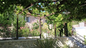 A stone wall with a staircase leading up to a building with a window. - Les Terrasses de la Roque Alric (La Roque-Alric)