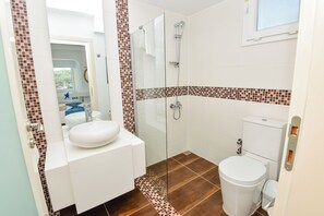 Ein modernes Badezimmer mit Duschkabine aus Glas, einem weißen Waschbecken und einer Toilette.