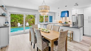 Cocina moderna con comedor, ventanas amplias y vista a una piscina.