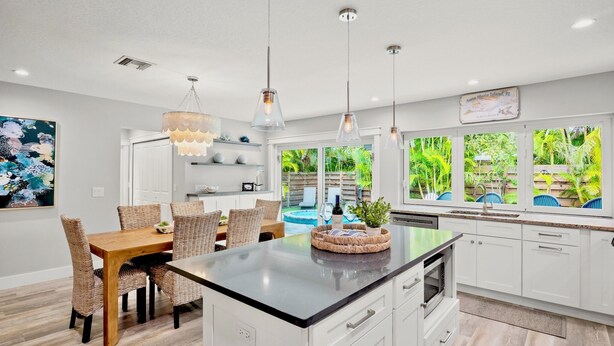 Una cocina moderna con armarios blancos, una isla central e iluminación colgante.