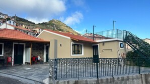 A building with a red-tiled roof, a stone facade, and a green door. - Your retreat between turquoise shores and forested paths (Machico)