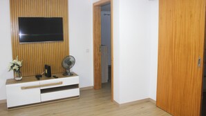 A room with a wooden panel wall, a flat-screen TV mounted above a white entertainment unit, and a wooden wardrobe. - Your retreat between turquoise shores and forested paths (Machico)