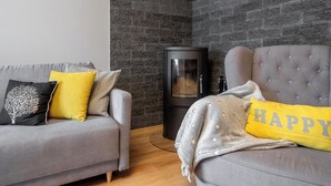 Una sala moderna con un sofá gris, un mueble negro y un sillón gris.