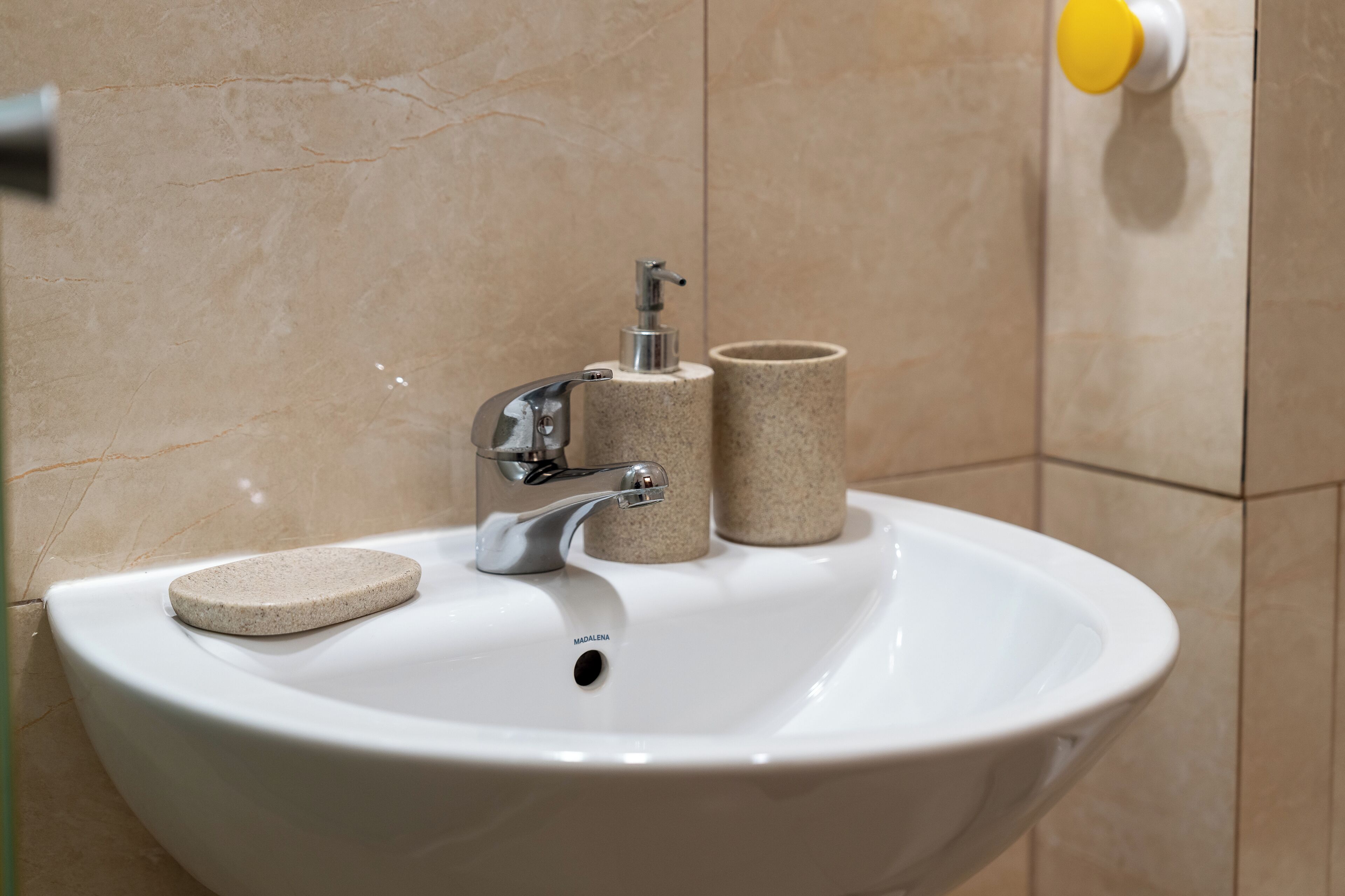 A bathroom sink with a soap dispenser and two cylindrical containers.
