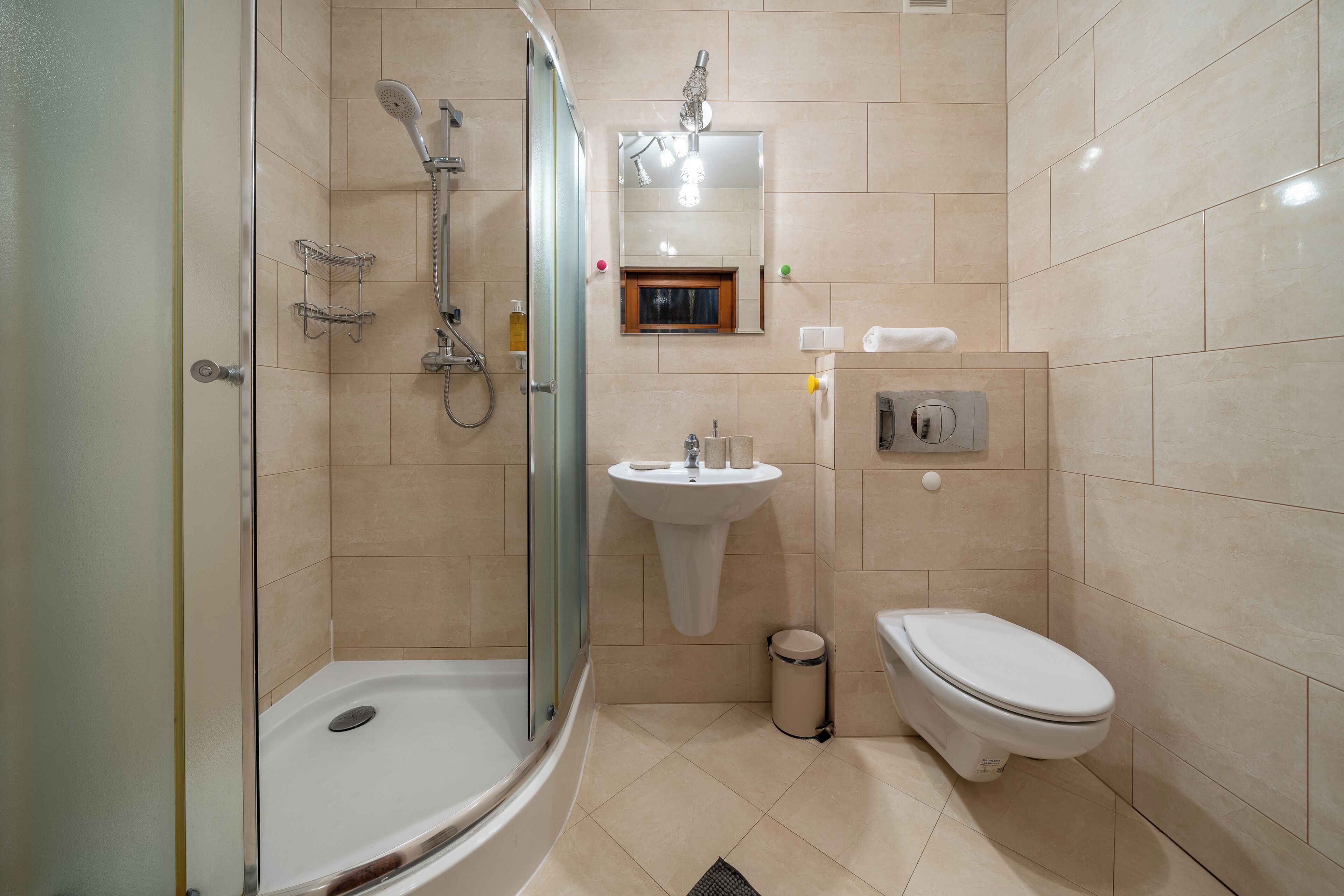 Een moderne badkamer met een douchecabine van glas, een wastafel op een voetstuk en een toilet.