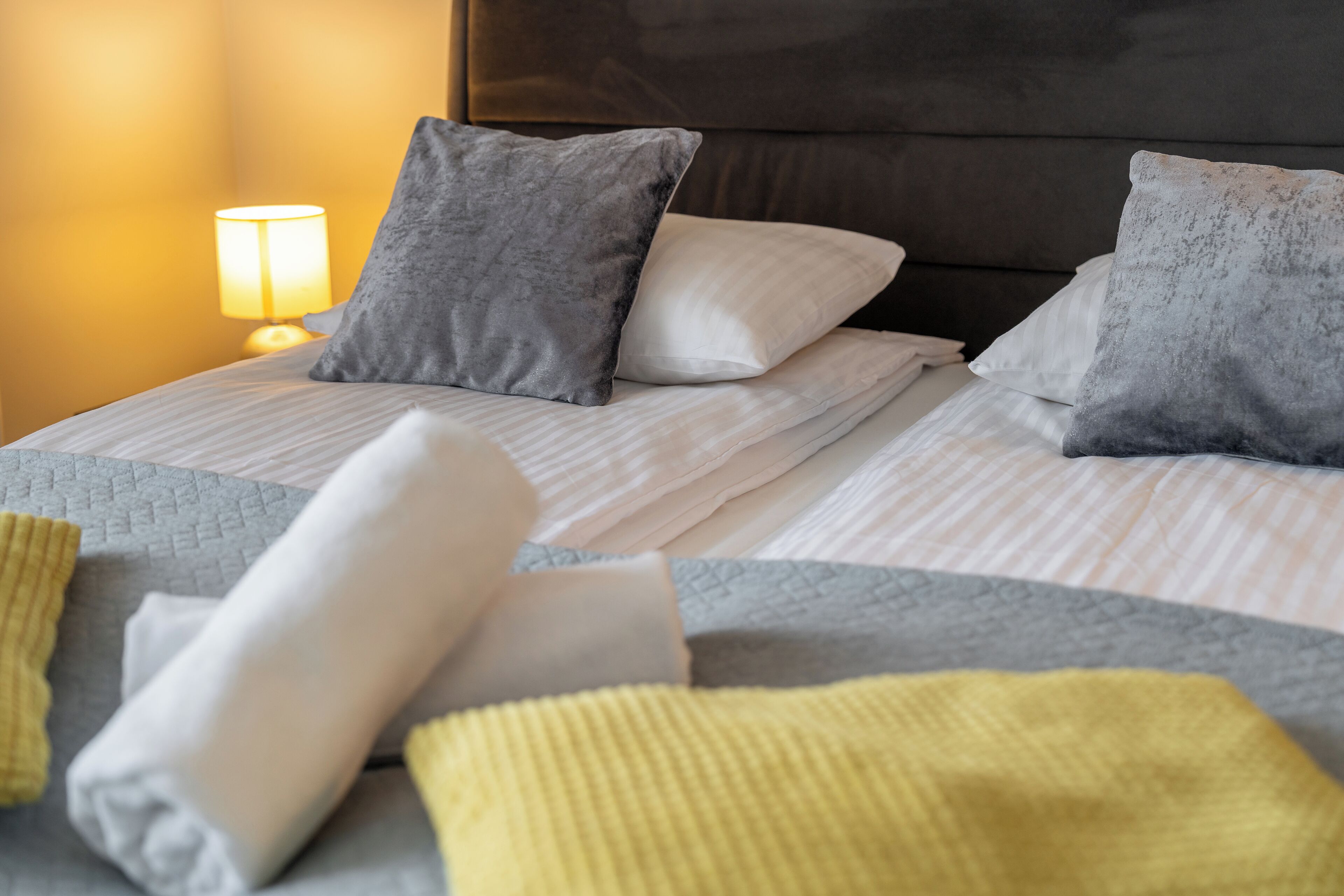 Una cama bien hecha con un edredón gris y blanco, una almohada gris y una almohada blanca.