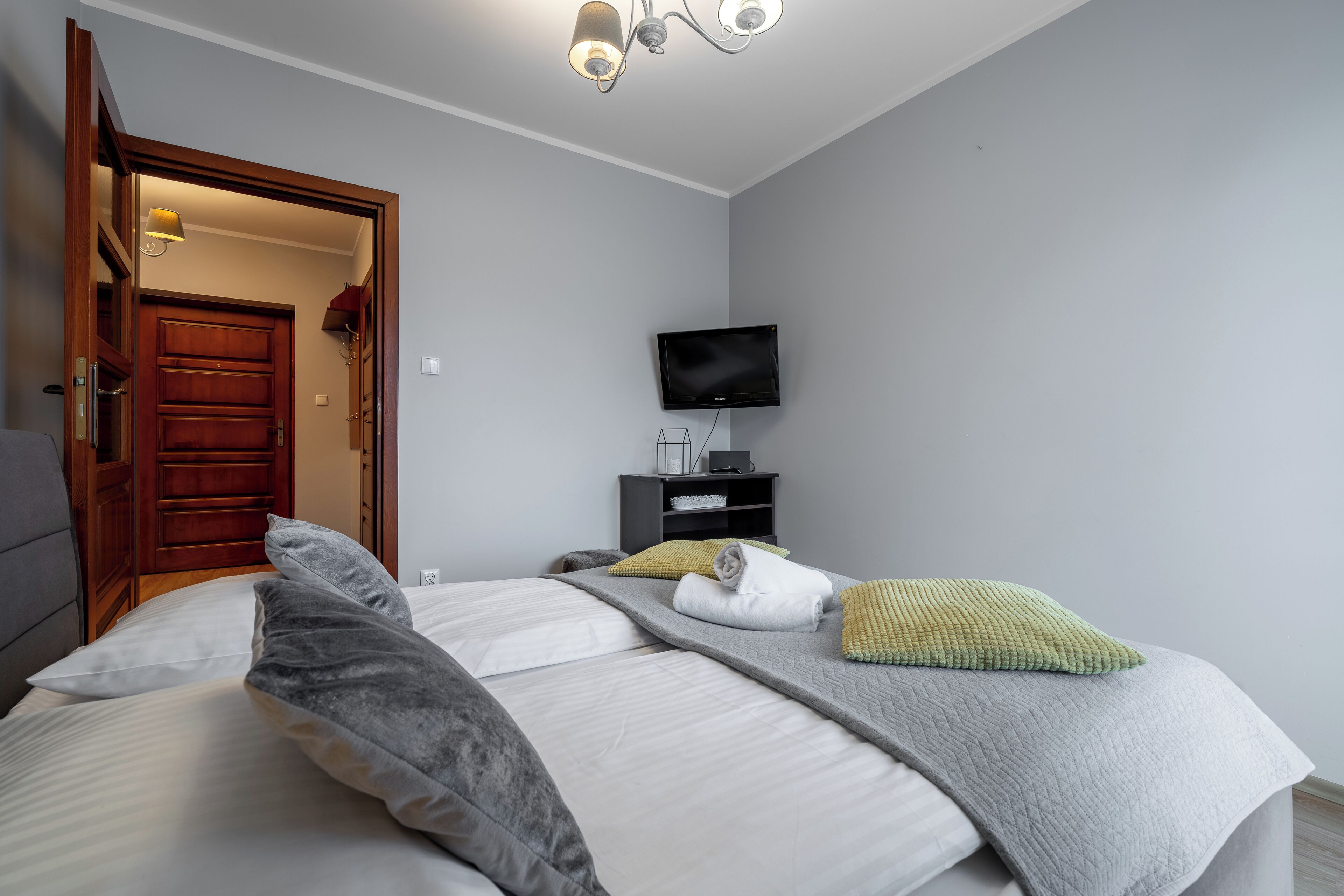 A hotel room with a bed, a television, a desk, and a door.