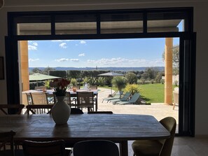 Una terrazza aperta con tavolo e sedie, un vaso con fiori e vista sul paesaggio.