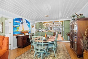 A dining area with a round table, chairs, and a painting of a sailboat.