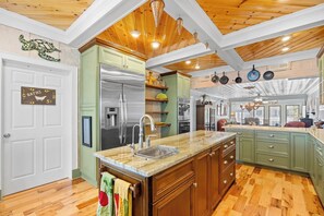 Una cocina con armarios de madera, un refrigerador de acero inoxidable y una encimera de mármol.
