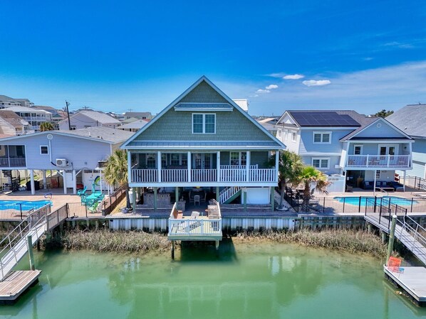 A two-story house with a balcony, a dock, and a swimming pool.