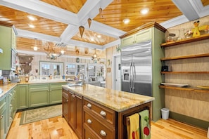 A spacious kitchen with wooden ceiling beams, a central island, and built-in appliances.