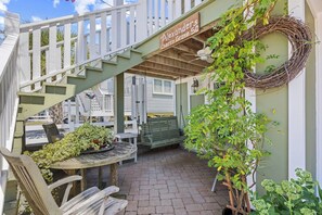 A covered outdoor area with a wooden table, chairs, a swing, and a staircase.