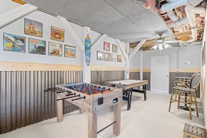 Ein Zimmer mit einer Fußballstoßmaschine, einem Billardtisch und verschiedenen Postern an den Wänden.