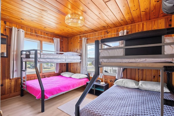 Eine Holzhütte mit Holzwänden und -decken, Etagenbetten, einem Fenster und einem Nachttisch.