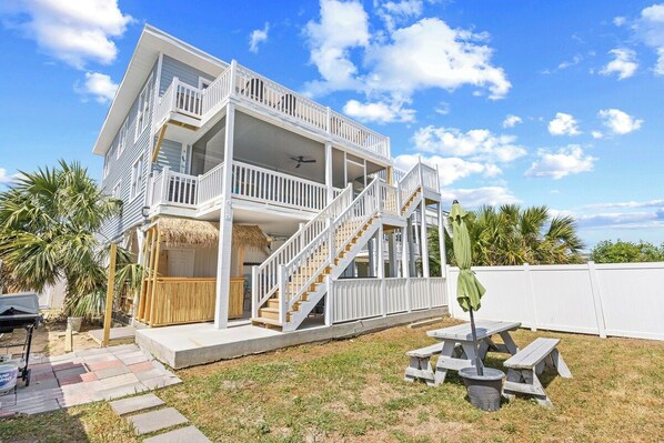 A two-story house with a balcony, a staircase, and a patio area with a table and chairs.