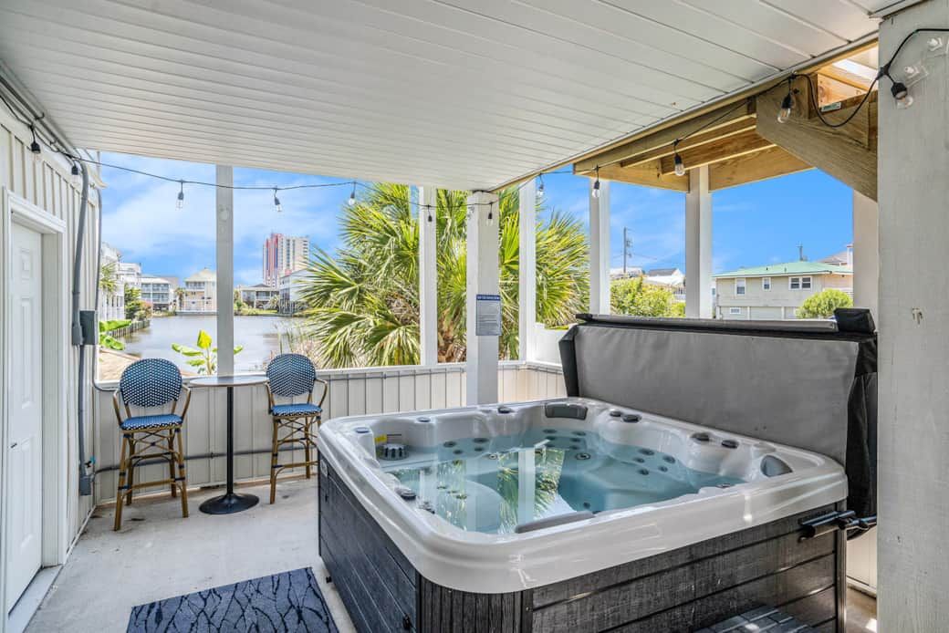 Un espace extérieur abrité comprenant un jacuzzi, deux chaises et une table.