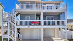 A two-story house with a balcony, a garage, and a front door.