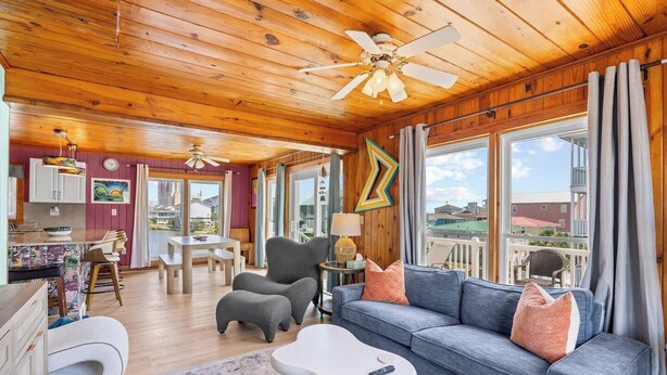 A cozy cabin with a wooden interior, a dining area, a sofa, and a view of the outside.